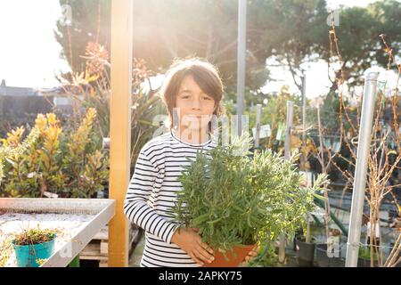 Portrait des Jungen mit Topfpflanzen in der Pflanzenkirnerei Stockfoto