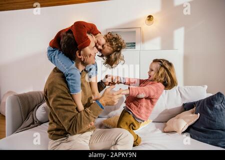 Vater spielt mit Töchtern auf der Couch Stockfoto