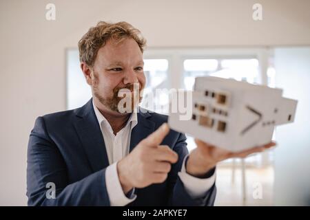 Geschäftsmann, der Architekturmodell im Büro hält Stockfoto