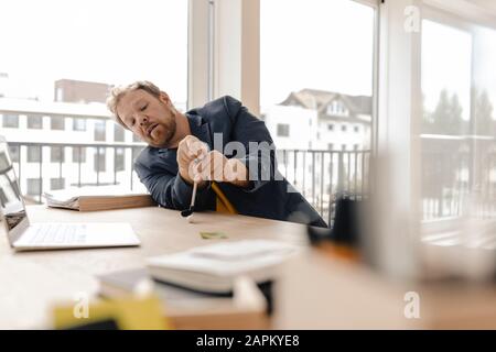 Geschäftsmann, der auf dem Schreibtisch im Büro Golf spielt Stockfoto