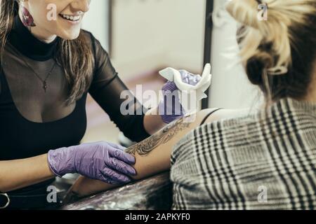 Tätooistische Frauen, die den Oberarm der weiblichen Kundin tätowieren Stockfoto