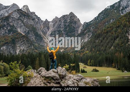Wanderer auf Aussichtspunkt mit erhobenen Armen in Laghi di Fusine, Friuli Julisch Venetien, Italien Stockfoto