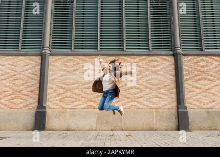 Aufgeregt hüpfte junge Frau in der Stadt Stockfoto