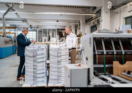 Zwei Geschäftsleute auf Papierstapel in einer Fabrik Stockfoto