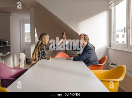 Unternehmer und Unternehmerin hohe Fiving im Büro Stockfoto