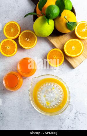 Entsafter, reife Zitrusfrüchte und Gläser frisch gepressten Orangensaft Stockfoto