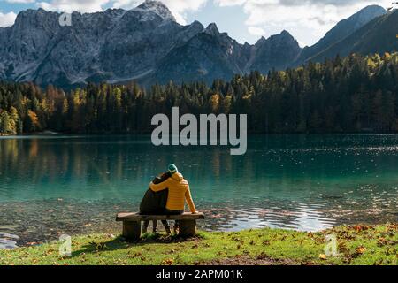 Rückansicht des Paares, das auf der Bank in Laghi di Fusine, Friuli Julisch Venetien, Italien sitzt Stockfoto