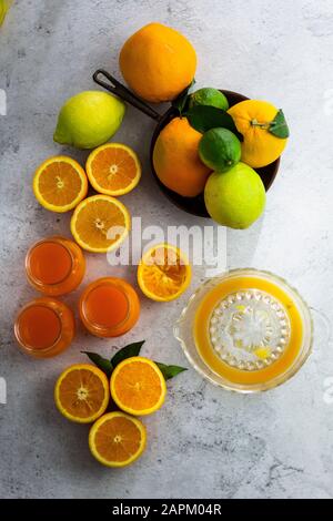 Entsafter, reife Zitrusfrüchte und Gläser frisch gepressten Orangensaft Stockfoto