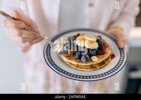 Nahaufnahme der Frau, die einen Teller mit Pfannkuchen und Obst hält Stockfoto