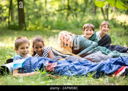 Schulkinder kampieren im Wald und liegen in Schlafsäcken Stockfoto
