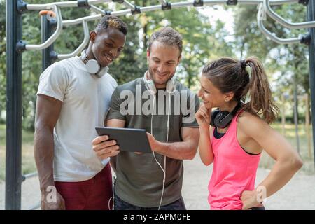 Freunde, die eine Pause vom Trainieren beim betrachten von Phablet haben Stockfoto