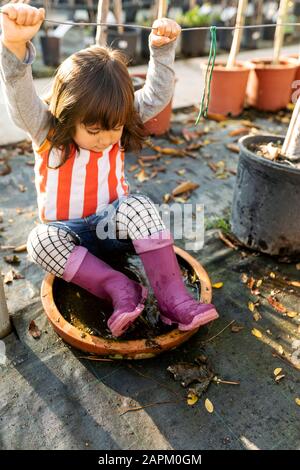 Kleines Mädchen, das Wellington Stiefel trägt, spielt in der Kinderkrippe Stockfoto