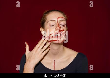 Porträt der jungen Frau, die Farbe auf ihr Gesicht schmiert Stockfoto