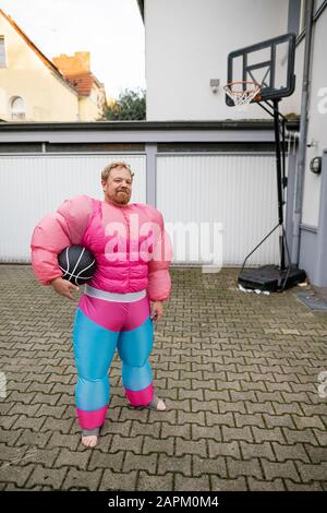 Porträt eines Mannes mit Basketball mit pinkfarbenem Bodybuilder-Kostüm Stockfoto