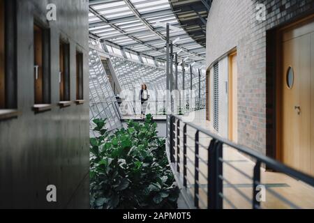 Geschäftsfrau steht auf einem Skywalk im modernen Bürogebäude Stockfoto