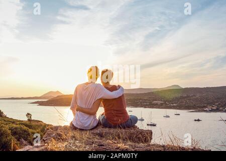 Ein Paar, das den Sonnenuntergang am Kap Sounion, Attika, Griechenland beobachtet Stockfoto