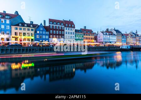 Dänemark, Kopenhagen, Lichtwege vor einer Reihe von bunten Wohngebäuden am Nyhavn Hafen Stockfoto