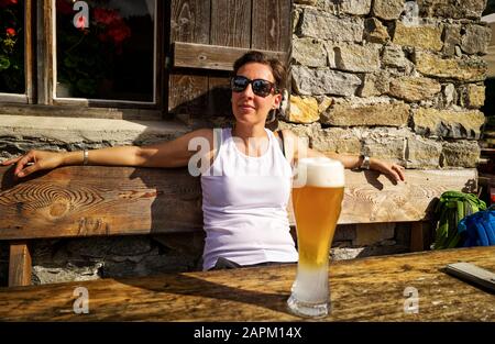 Sonnenschein und Weizenbier genießen Frau in einer Berghütte, Passeiertal, Südtirol, Italien Stockfoto