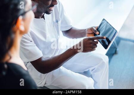 Zahnärztin mit Tablette spricht mit weiblicher Patientin in der Zahnchirurgie Stockfoto