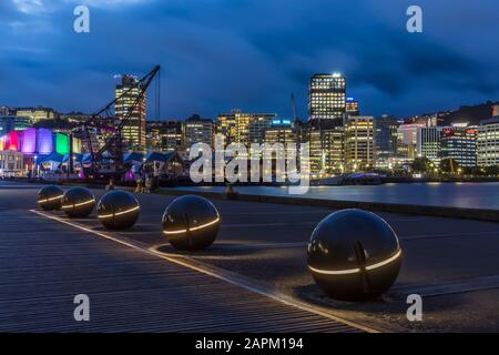 Neuseeland, Wellington, Lichtkugeln am Hafen bei Nacht mit beleuchteter Skyline im Hintergrund Stockfoto