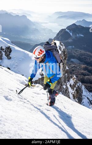 Alpinist, der einen verschneiten Berg aufsteigt, Orobie Alps, Lecco, Italien Stockfoto