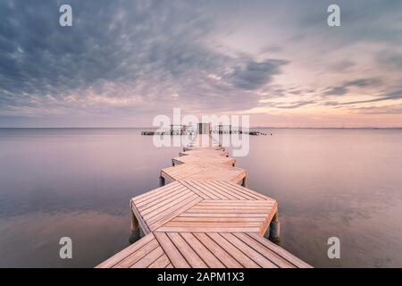 Spanien, Murcia, Santiago de la Ribera, Holzsteg auf ruhigem Meer bei Sonnenuntergang Stockfoto