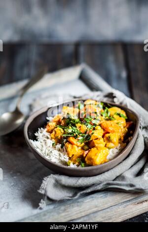 Schale veganes Curry mit Kartoffeln, Karotten, Erbsen, Petersilie und Kürbis Stockfoto