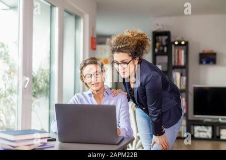 Zwei Geschäftsfrauen mit Laptop zu Hause Stockfoto