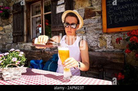 Frau, die in einer Berghütte, Passeiertal, in Südtirol, Italien, ein Weizenbier gießt Stockfoto