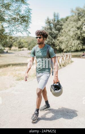 Junger Mann mit Helm, der im Park spazieren geht Stockfoto