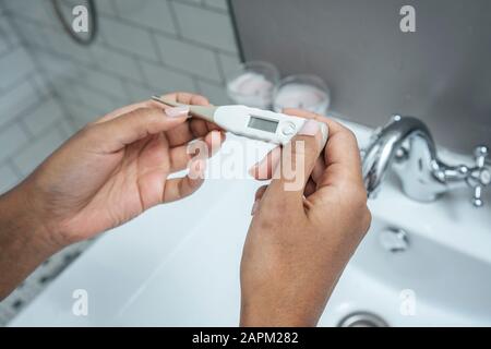Nahaufnahme der Frau, die Thermometer im Badezimmer hält Stockfoto
