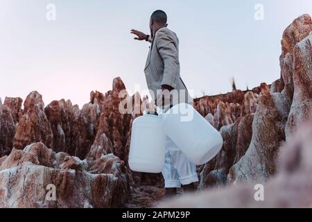 Leerer junger Mann kann in unfruchtbarem Land nach Wasser suchen Stockfoto