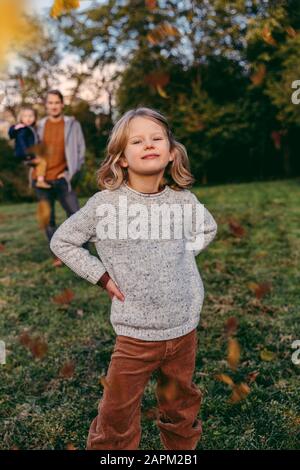 Porträt des selbstbewussten Mädchens mit ihrer Familie auf einer Wiese im Herbst Stockfoto