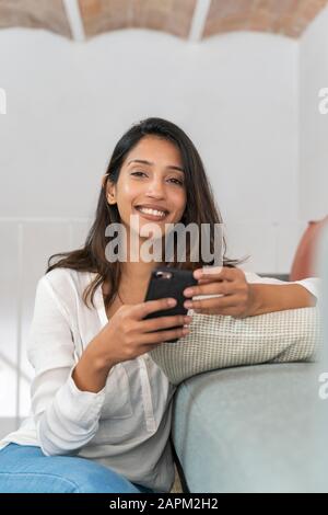 Porträt einer entspannten jungen Geschäftsfrau mit Smartphone im Studio Stockfoto