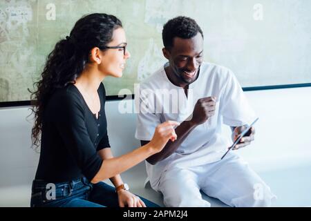 Zahnärztin mit Tablette spricht mit weiblicher Patientin in der Zahnchirurgie Stockfoto