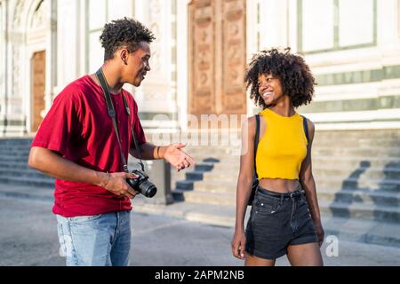 Fröhliches junges Touristenpaar, das in der Stadt, Florenz, Italien, spazieren geht und spricht Stockfoto