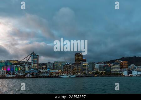 Neuseeland, Wellington, Wolken über der Skyline der Stadt am Wasser bei Dämmerung Stockfoto