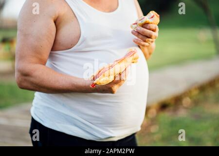 Mann mit Bierbauch, der Sandwich hält Stockfoto