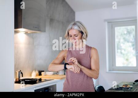 Frau mit Smartwatch in der Küche zu Hause Stockfoto