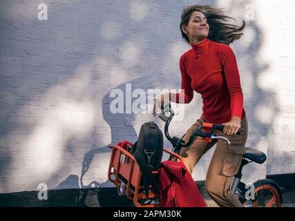 Unbeschwerte junge Frau mit einem Leihfahrrad Stockfoto