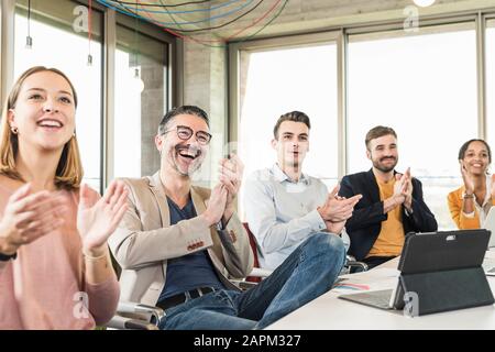 Glückliche Geschäftsleute, die während einer Besprechung im Sitzungssaal applaudieren Stockfoto