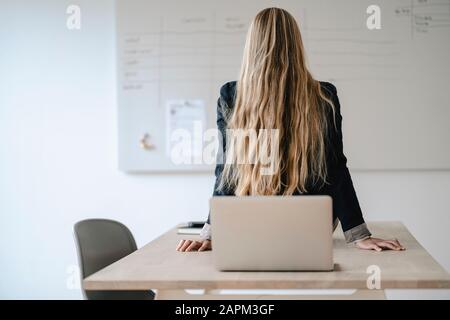 Rückansicht der jungen Geschäftsfrau, die auf dem Schreibtisch im Büro Turnen macht Stockfoto
