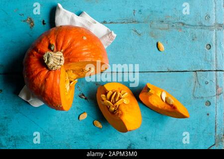 Roter Kürbis (Cucurbita maxima) auf blauem Schneidebrett Stockfoto