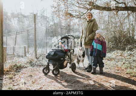 Mutter mit Kindern und Grenzkollie bei Waldspaziergang im Herbst Stockfoto