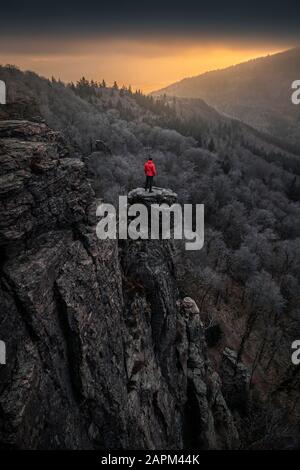 Mann steht bei Sonnenaufgang auf der Felsnadel am Battert-Felsen, Baden-Baden, Deutschland Stockfoto