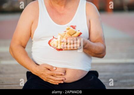 Mann mit Bierbauch, der Sandwich hält Stockfoto