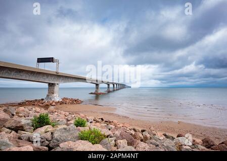 Kanada, Prince Edward Island, wolkiger Himmel über dem felsigen Strand und der Confederation Bridge Stockfoto