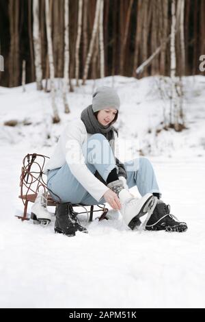 Frau, die Eiskaten auf dem Schneefeld anlegt Stockfoto