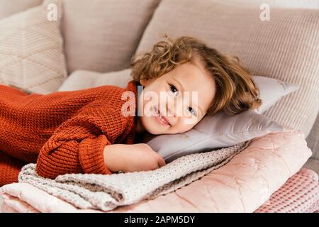 Porträt eines lächelnden Mädchens, das zu Hause auf der Couch liegt Stockfoto