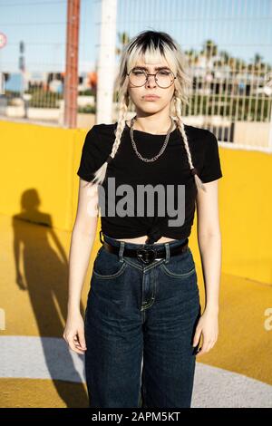 Porträt der jungen Frau mit gefärbtem Haar mit einer metallumrandeten Brille Stockfoto